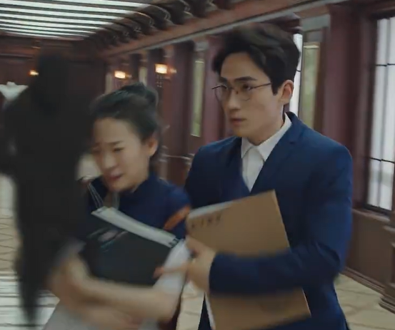 A man and woman turn the corner of the hallway.