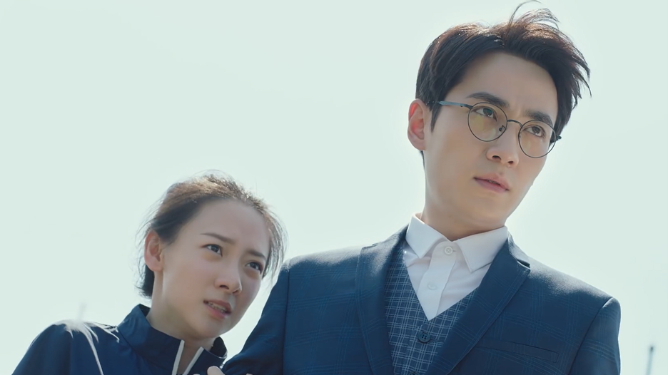 A man stands protectively in front of a woman.