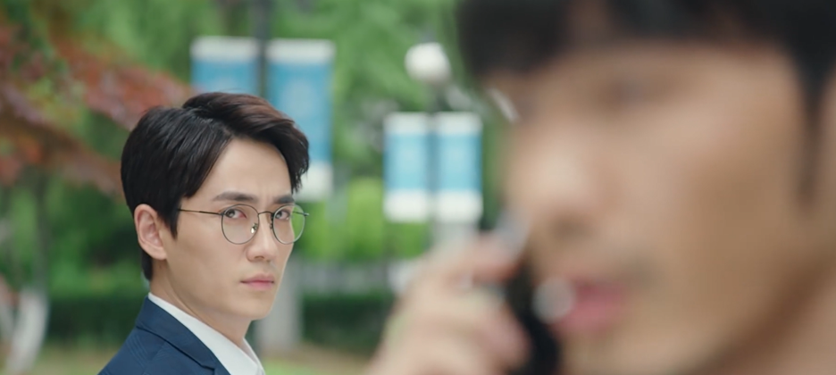 A man in the background looks at the man in the foreground.
